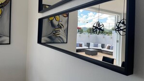 A modern room with a large mirror reflecting an outdoor seating area.