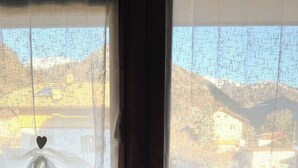 Quarto com duas janelas, cada uma com uma cortina branca transparente e uma decoração em formato de coração.