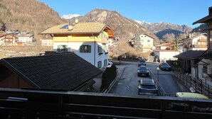 Uma vila montanhosa com arquitetura tradicional, uma rua principal e vista para montanhas nevadas.