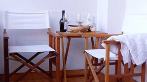 Um quarto pequeno e simples com uma mesa de madeira e duas cadeiras. Há uma garrafa e copos na mesa.