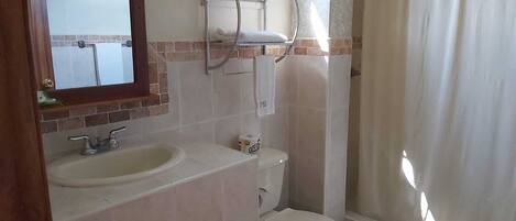 Baño con lavamanos, inodoro y cortina de ducha.