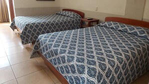 A hotel room with two beds, a small table, a chair, a wall-mounted lamp, and a framed picture on the wall. - Hotel Playa Bonita (Tela)
