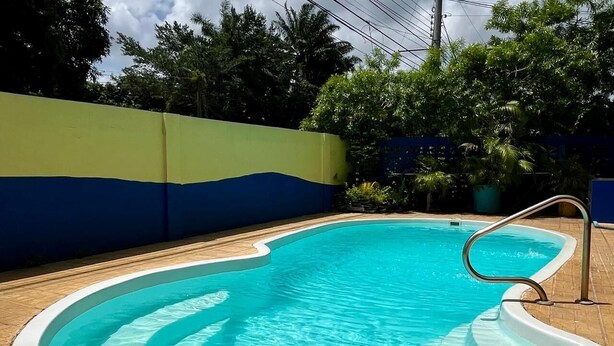 A swimming pool with a curved edge, surrounded by a brick patio. - Hotel Playa Bonita (Tela)