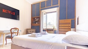 A bedroom with a bed, a desk, a chair, a wardrobe, a television, and a window. - Elegantis.it La ParioLina Apartment (Roma)