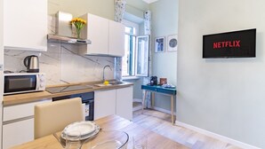 A modern kitchen with a microwave, kettle, and a dining table set with plates and glasses. - Elegantis.it La ParioLina Apartment (Roma)