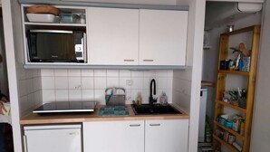 A compact kitchen with white cabinets, a microwave, a sink, and a small refrigerator. - Appartement 2 pièces sur le Port du Crouesty, à louer pour les vacances (ARZON)