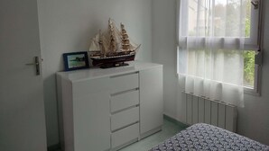 A room with a white cabinet, a model ship, and a window with sheer curtains. - Appartement 2 pièces sur le Port du Crouesty, à louer pour les vacances (ARZON)