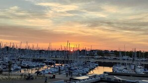 A marina with numerous boats docked, a sunset in the background, and a few people walking around. - Appartement 2 pièces sur le Port du Crouesty, à louer pour les vacances (ARZON)