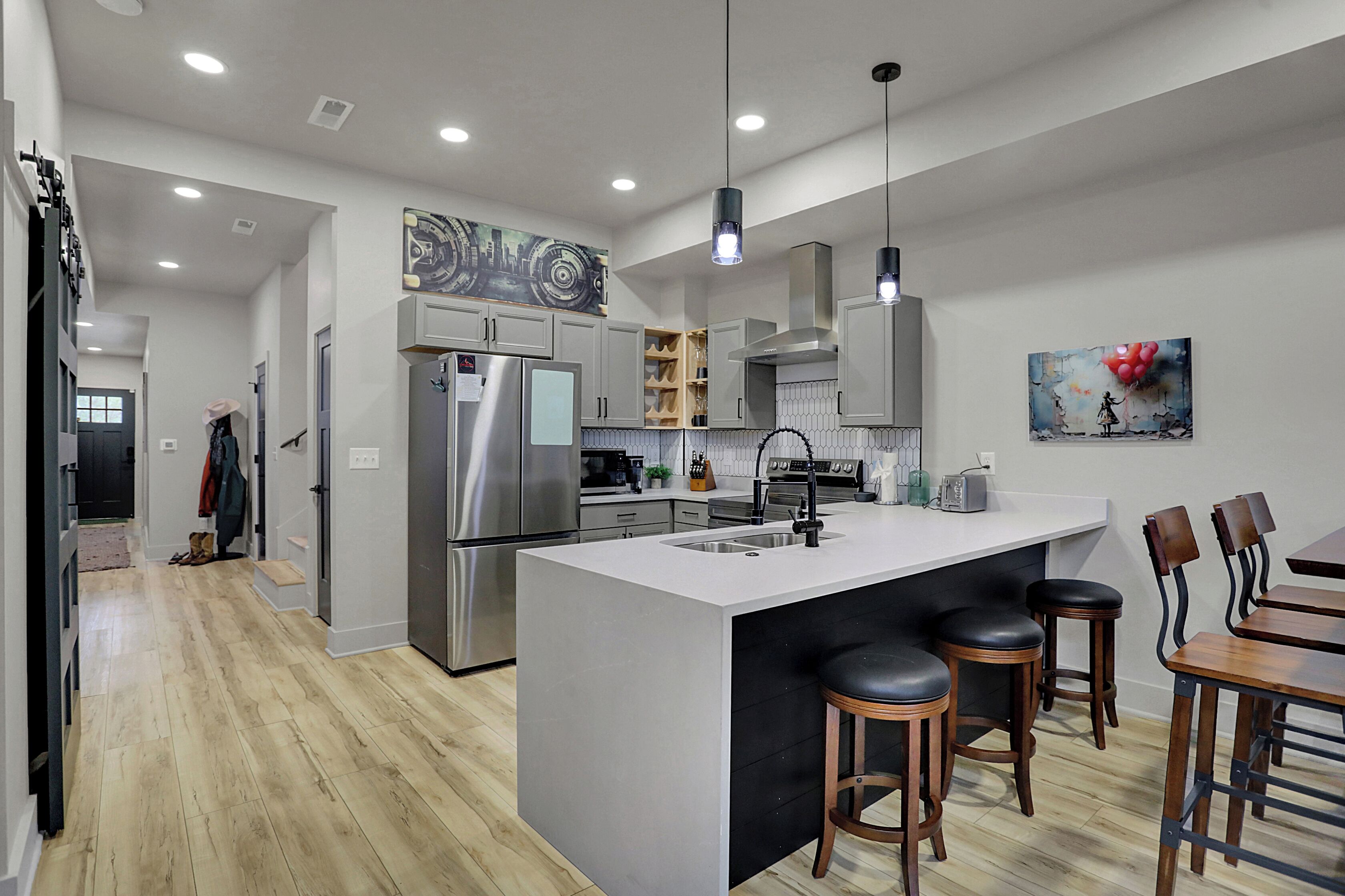 A modern kitchen with a large island, stainless steel appliances, and wooden bar stools.