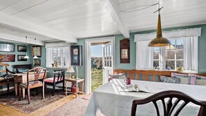 A cozy room with a large bed, a wooden table, and chairs. There is a window with a view of the outdoors. - 4 bedroom gorgeous home in Fanø (Fanø)