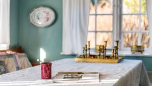 A table with a book and a mug, a brass candlestick holder, and a window with curtains. - 4 bedroom gorgeous home in Fanø (Fanø)