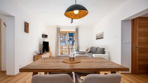 A dining area with a wooden table, two chairs, a hanging light fixture, and a view to a balcony. - Apartment 'Jan's  Am See' with Lake View, Balcony and Wi-Fi (Pracupola)