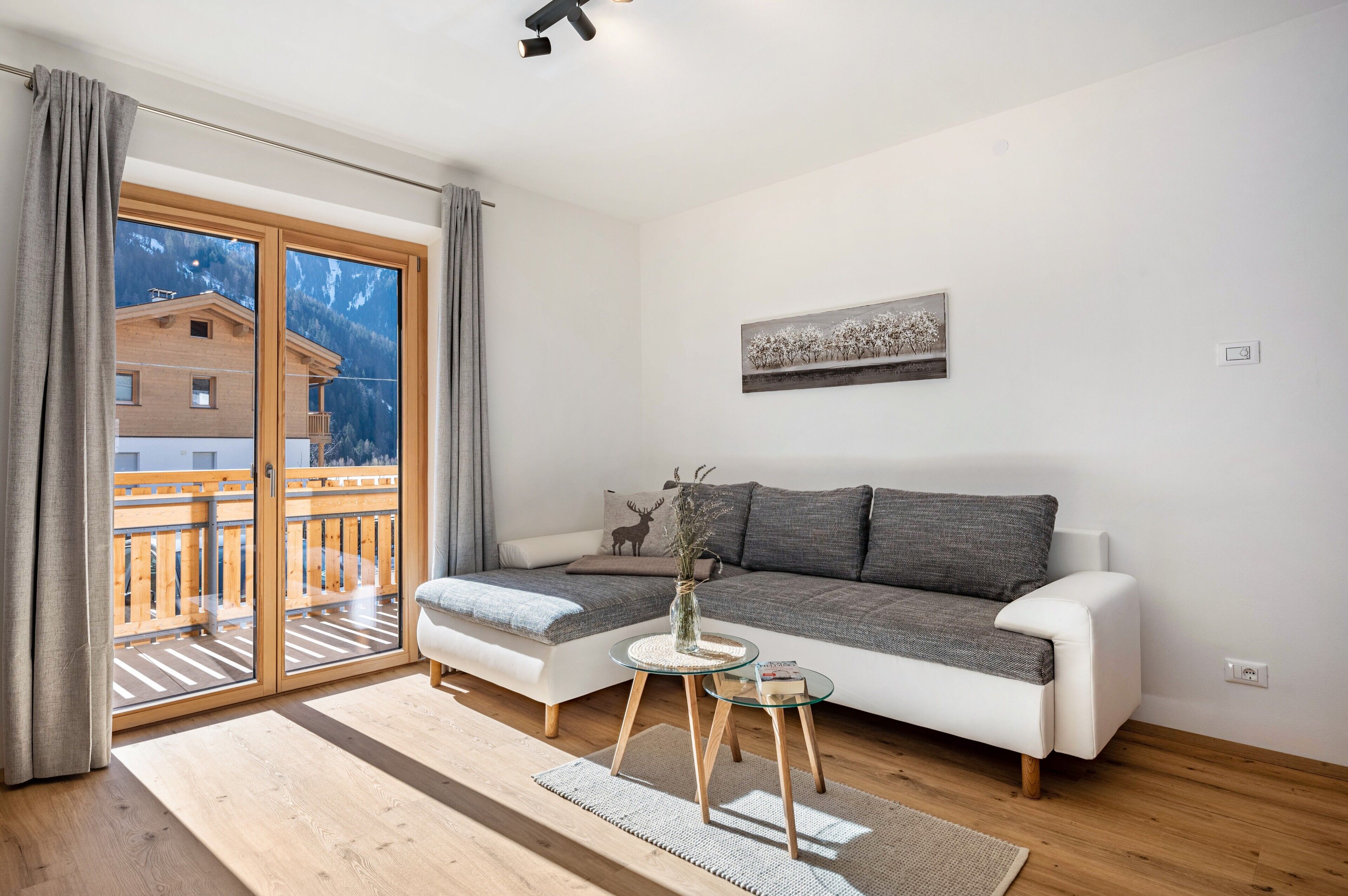 Ein modernes Wohnzimmer mit einer Couch, einem kleinen Tisch, einer Vase und einem Bild an der Wand.