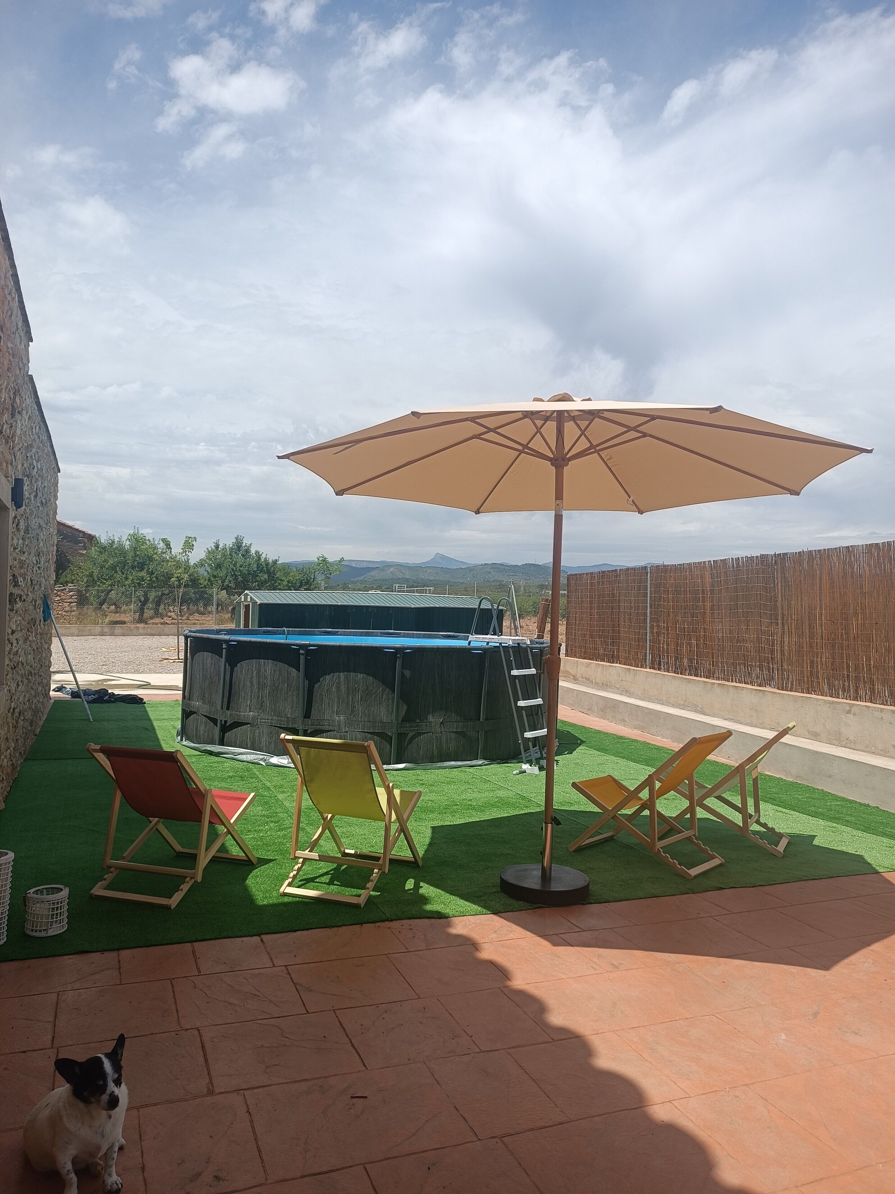 A patio with artificial grass, a pool, and a wooden fence.
