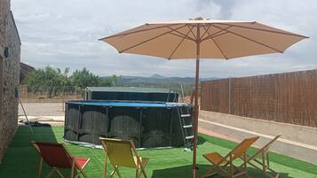 A patio with artificial grass, a pool, and a wooden fence.