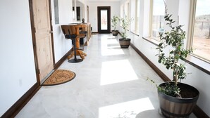 A hallway with a wooden door, a dining area with a table and chairs, and potted plants. - Wingate House at Sand Creek Homestead (Torrey)