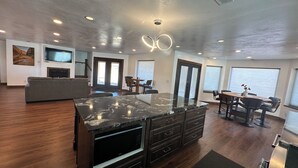 A modern kitchen with a marble island, built-in microwave, and dark wood cabinetry. - Wingate House at Sand Creek Homestead (Torrey)
