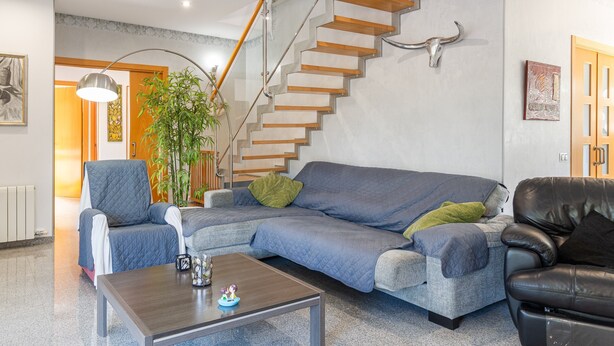 A living room with a staircase, a sofa set, a coffee table, and a lamp.