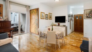 A dining area with a table, chairs, a chandelier, and a television.