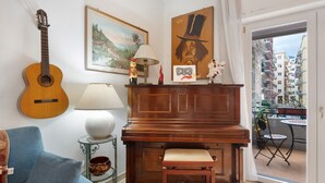 A living room with a piano, a guitar, a sofa, a lamp, and a painting.