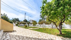 A paved courtyard with stone tiles, a tree, and a building in the background. - Apartment 'Lotus 1' with Sea View, Wi-Fi and Air Conditioning (Corfu)