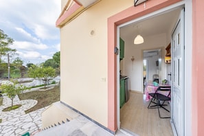 A residential property with a patio, a dining area with a table and chairs, and a kitchen visible through an open door. - Apartment 'Lotus 1' with Sea View, Wi-Fi and Air Conditioning (Corfu)