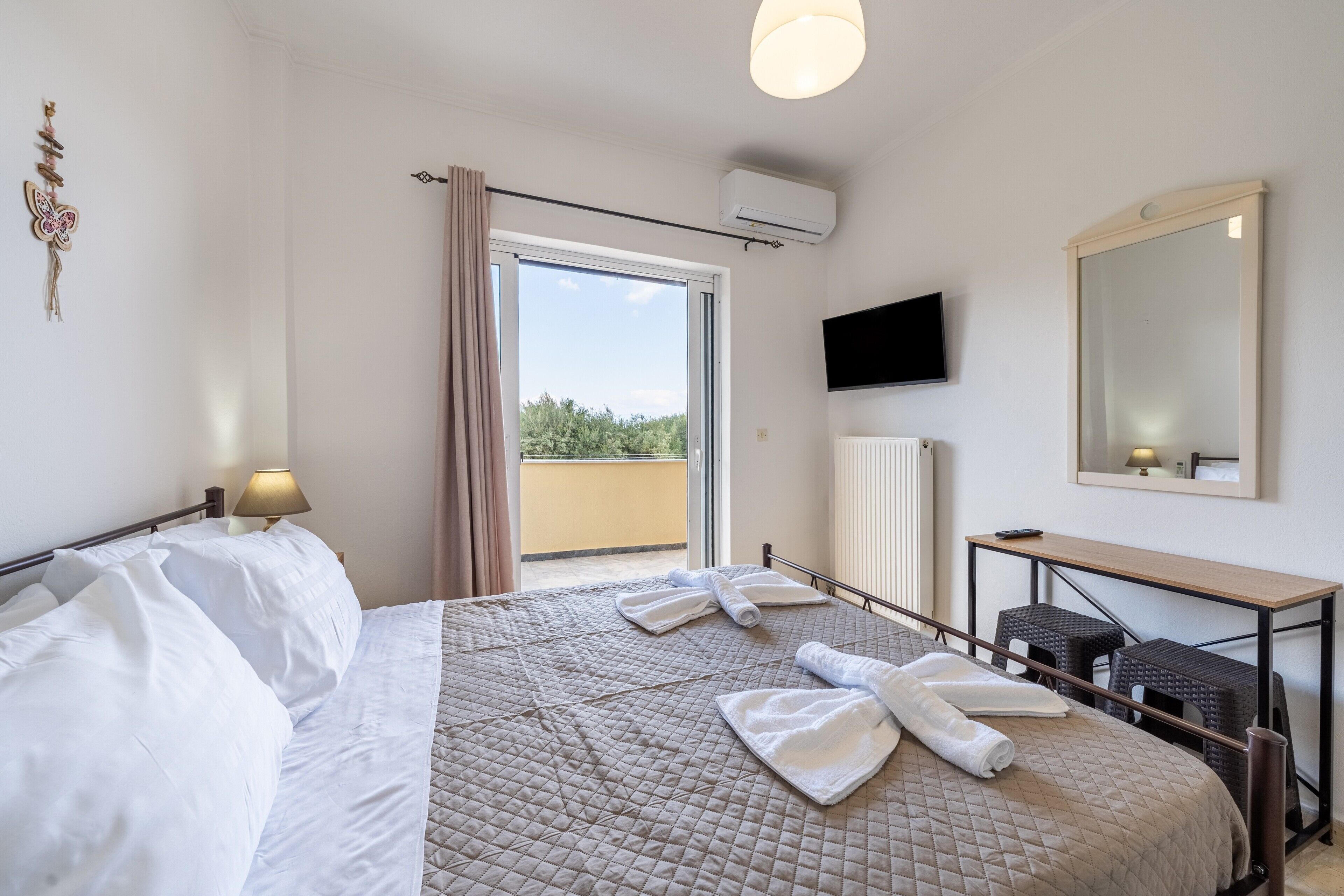 Hotellihuone, jossa on sänky, työpöytä, televisio ja parveke.