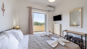 A hotel room with a bed, a desk, a television, and a balcony. - Apartment 'Lotus 1' with Sea View, Wi-Fi and Air Conditioning (Corfu)