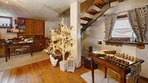 Un interior de madera con una mesa de comedor, un árbol decorativo y una escalera.