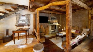 Un interior rústico con chimenea de piedra, vigas de madera, una mesa de madera y un banco.