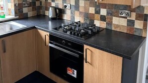Une cuisine moderne avec des meubles en bois, une cuisinière à gaz et un dosseret carrelé.