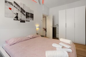 Een slaapkamer met een bed, een muur met kunstwerken, een kledingkast en een zichtbare badkamer door een open deur.