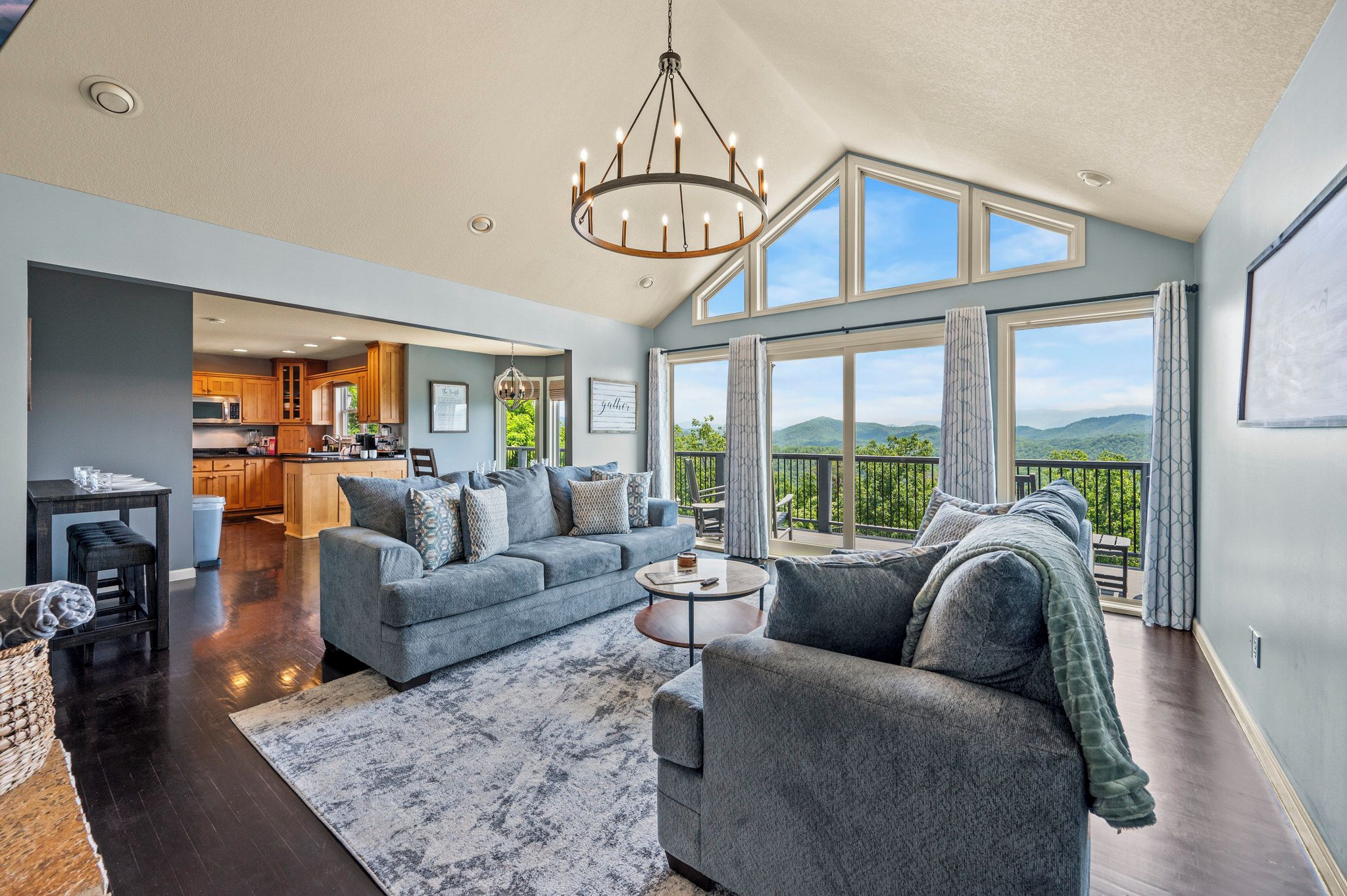 A spacious living room with a large window, a chandelier, and a view of the outdoors.