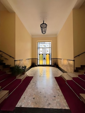 A grand staircase with red carpet runners leading to a large, ornate door with stained glass panels. - Apartment 'Grandi' with Balcony, Wi-Fi and Air Conditioning (Milano)