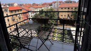 A balcony with a view of a cityscape, including buildings with red roofs and a clear sky.