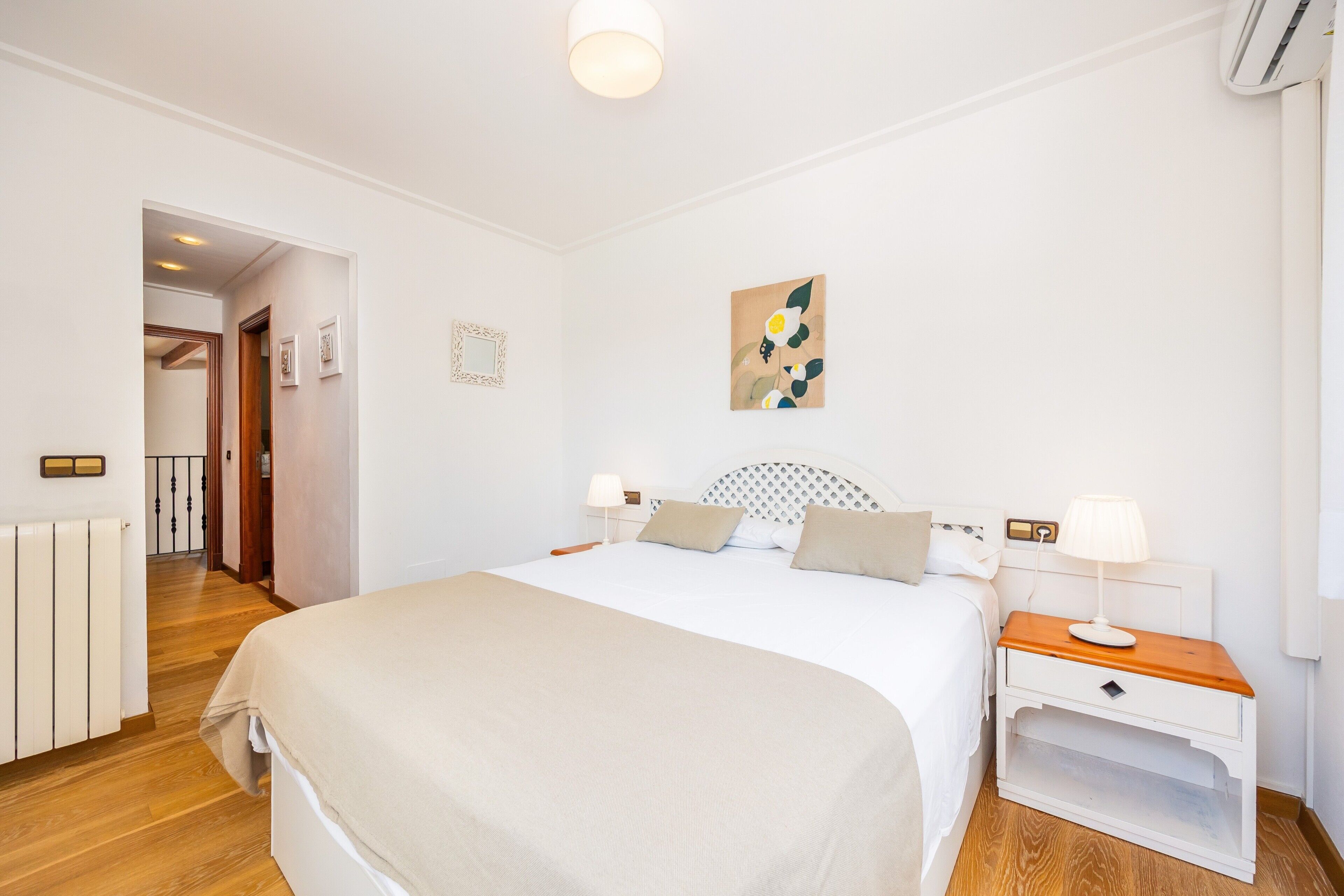 Une chambre à coucher comprenant un lit, des tables de chevet, un radiateur, une porte et une œuvre d’art accrochée au mur.