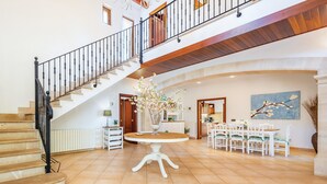 Un vaste espace de vie comprenant un escalier, une table à manger avec des chaises et une grande fenêtre.