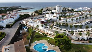 A coastal resort with multiple swimming pools, a marina, and a view of the sea.
