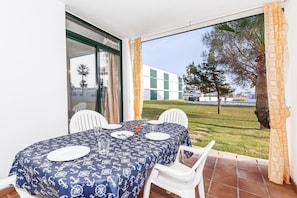 A dining area with a table set for four, a glass of water, and a bowl of fruit.