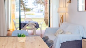 A room with a wooden table, a white sofa, a lamp, and a view of the outdoors.