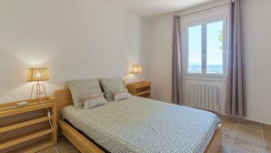 Un dormitorio con cama, mesitas de noche, lámparas, una ventana con cortinas y vistas.