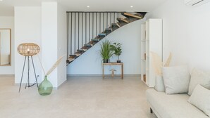 Una sala de estar moderna con una escalera, un sofá, una consola y una planta en maceta.