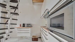 A modern kitchen with white cabinetry, a large built-in oven, and a microwave on the countertop.