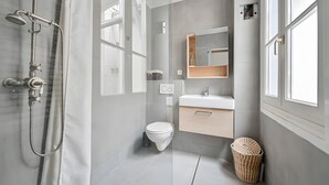 A modern bathroom with a shower, toilet, vanity, and a large mirror.