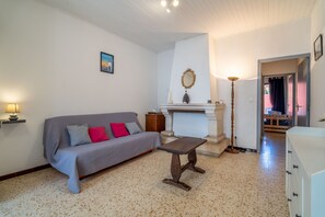 A living room with a sofa, a small table, a fireplace, and a lamp. - Holiday Home 'Maison De Pecheurs' with Private Terrace and Air Conditioning (Valras-Plage)