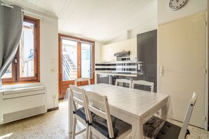 A compact kitchen with a dining table, chairs, and a window. - Holiday Home 'Maison De Pecheurs' with Private Terrace and Air Conditioning (Valras-Plage)