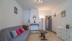 Habitació amb un sofà, una taula, un armari, un mirall i una porta que condueix a una altra habitació.