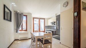 Cuina compacta amb taula de dinar, cadires, rellotge i porta que dona a una altra habitació.