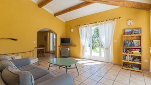 Una sala de estar con sofá, televisor, estantería y comedor.
