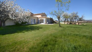 Una casa con jardín, césped y cielo azul despejado.